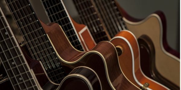 Close-up of several acoustic guitars with a dark background